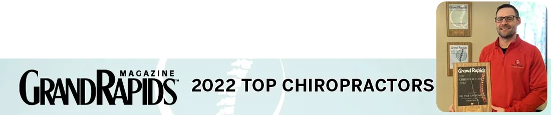 Promotional banner featuring Dr. Paul Kaminski recognized as one of Grand Rapids Magazine's "2022 Top Chiropractors." The individual holds a plaque, with awards displayed in the background.