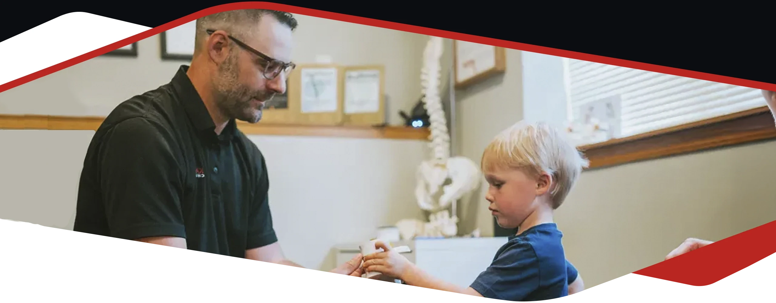 Dr. Paul Kaminski examines or adjusts a young child’s hand in an office environment.